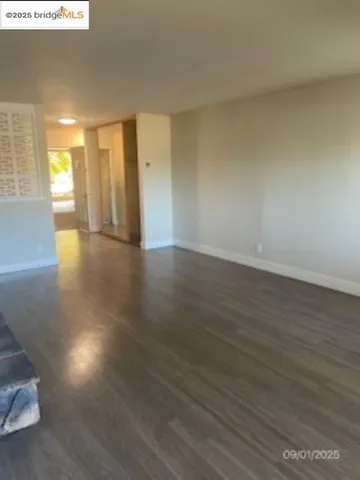 a view of an empty room with wooden floor and a window