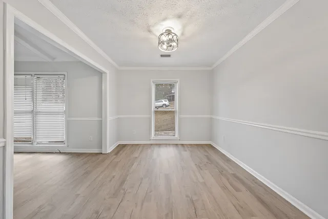 an empty room with wooden floor cabinet and windows