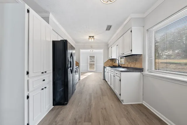 a kitchen with stainless steel appliances a refrigerator sink and wooden floor