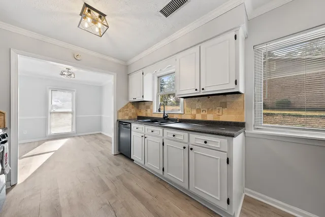 a kitchen with granite countertop a sink cabinets stainless steel appliances and a window