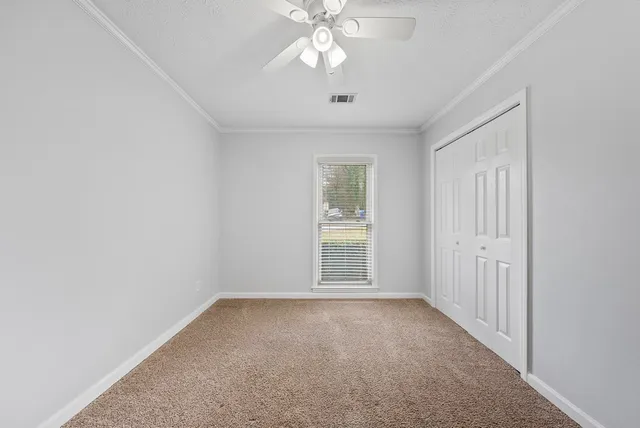 an empty room with chandelier fan and windows