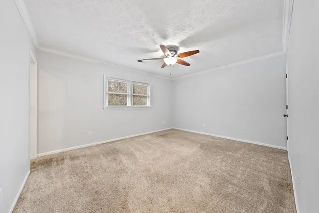 an empty room with a window and a fan