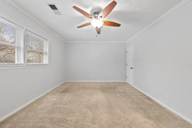 an empty room with windows and fan