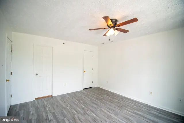a view of a room with wooden floor and a ceiling fan