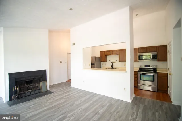 a living room with stainless steel appliances furniture a fireplace and wooden floor