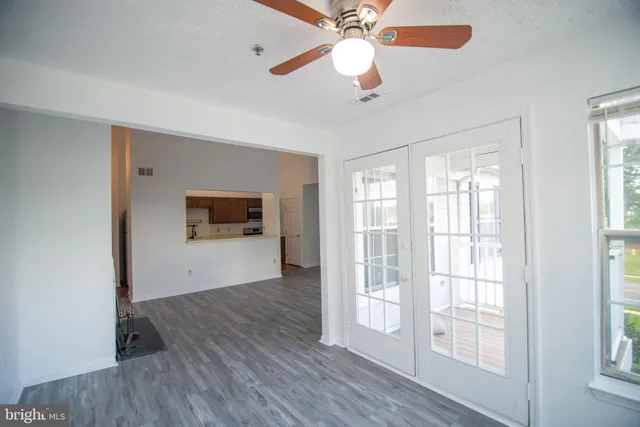 a view of an empty room with a window and wooden floor