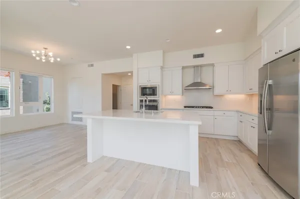 a kitchen with stainless steel appliances granite countertop a refrigerator a sink dishwasher a stove and white countertops with wooden floor