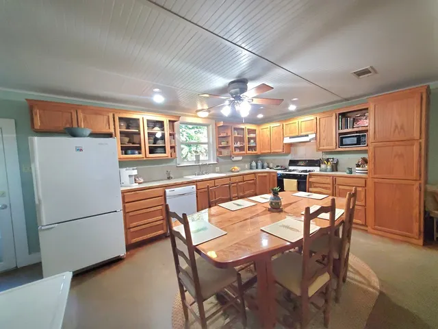 a kitchen with stainless steel appliances granite countertop a refrigerator a stove a sink a dining table and chairs