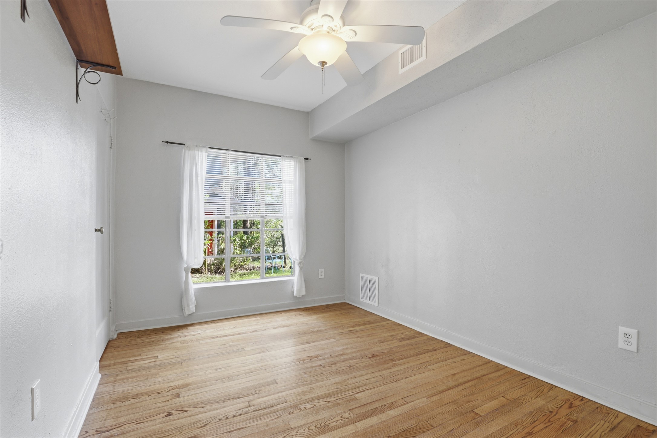 3901 Wrightwood Road, Unit A Austin, TX 78722 - Photo 10 of 11 Secondary bedroom featuring wood-finish flooring, light gray walls, and a ceiling fan.