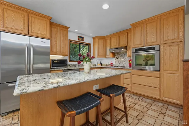 a kitchen with granite countertop cabinets stainless steel appliances a sink and a window