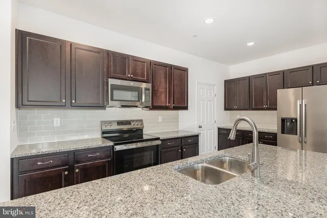 a kitchen with granite countertop a refrigerator stove top oven and sink