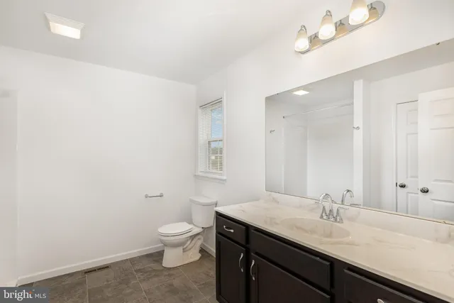 a bathroom with a granite countertop sink a toilet and a mirror