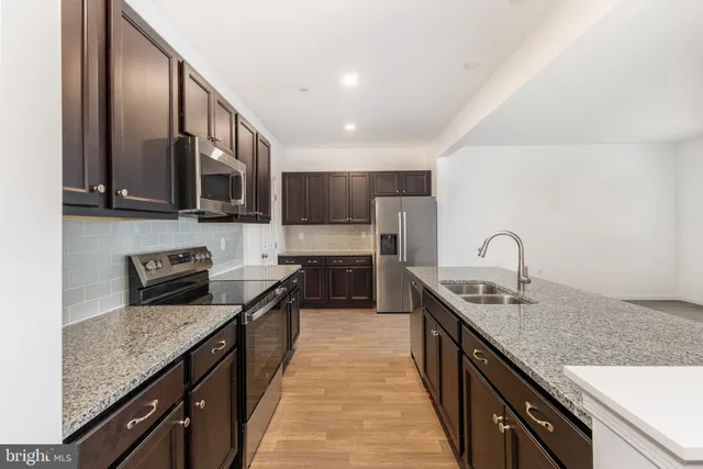 a kitchen with stainless steel appliances granite countertop a sink a stove top oven a counter space and cabinets