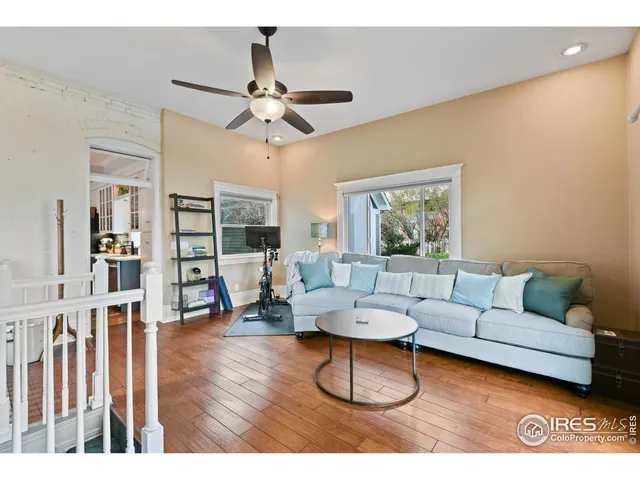 a hall with kitchen island granite countertop wooden floor a sink a counter top space and stainless steel appliances