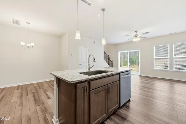 a large kitchen with granite countertop a sink a counter space stainless steel appliances and cabinets