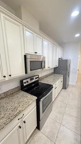 a kitchen with granite countertop a stove a sink and a refrigerator