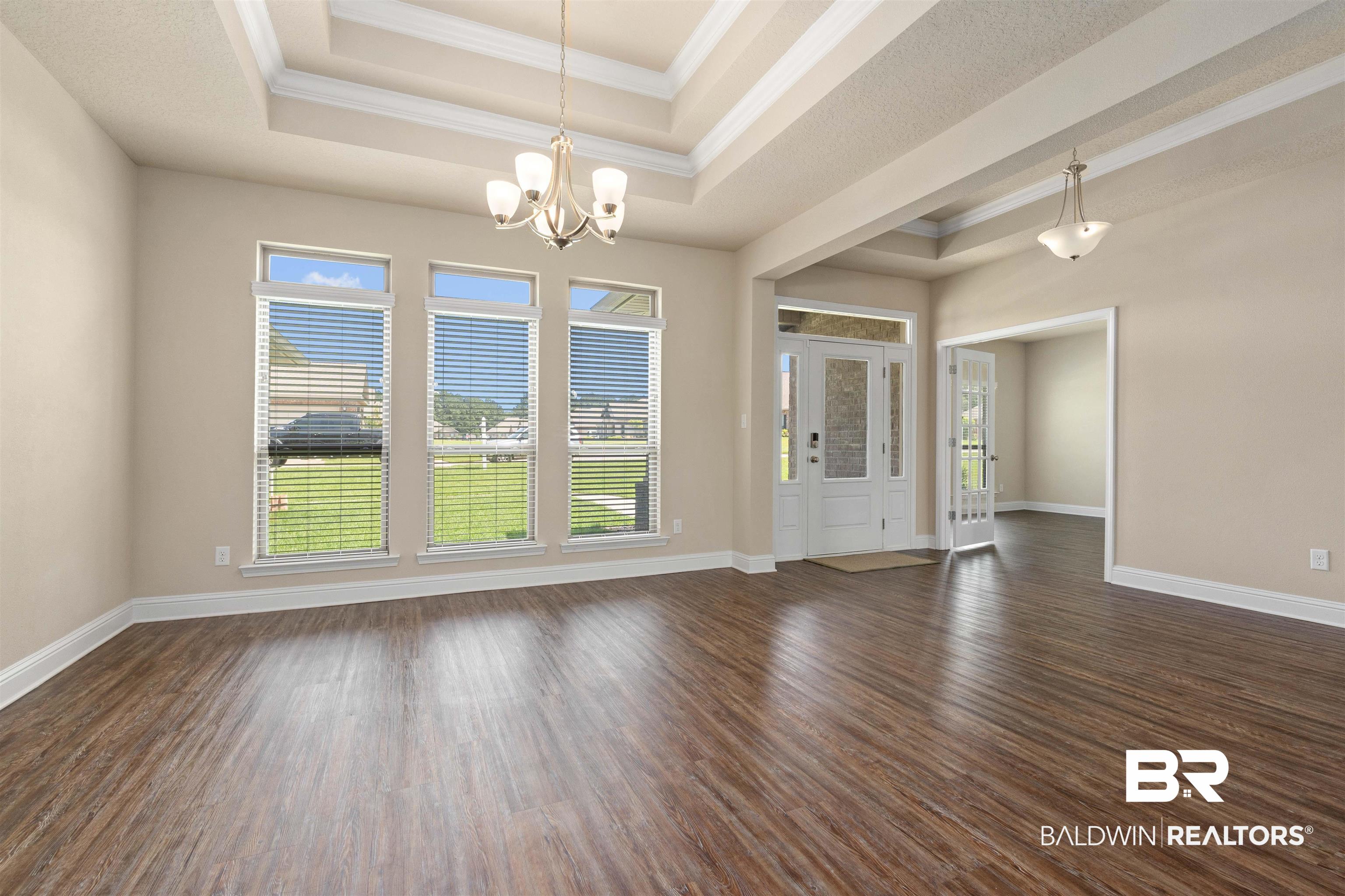 1864 Gwin Court Mobile, AL 36695 - Photo 16 of 37 Unfurnished living room featuring a tray ceiling, a notable chandelier, and dark hardwood / wood-style floors