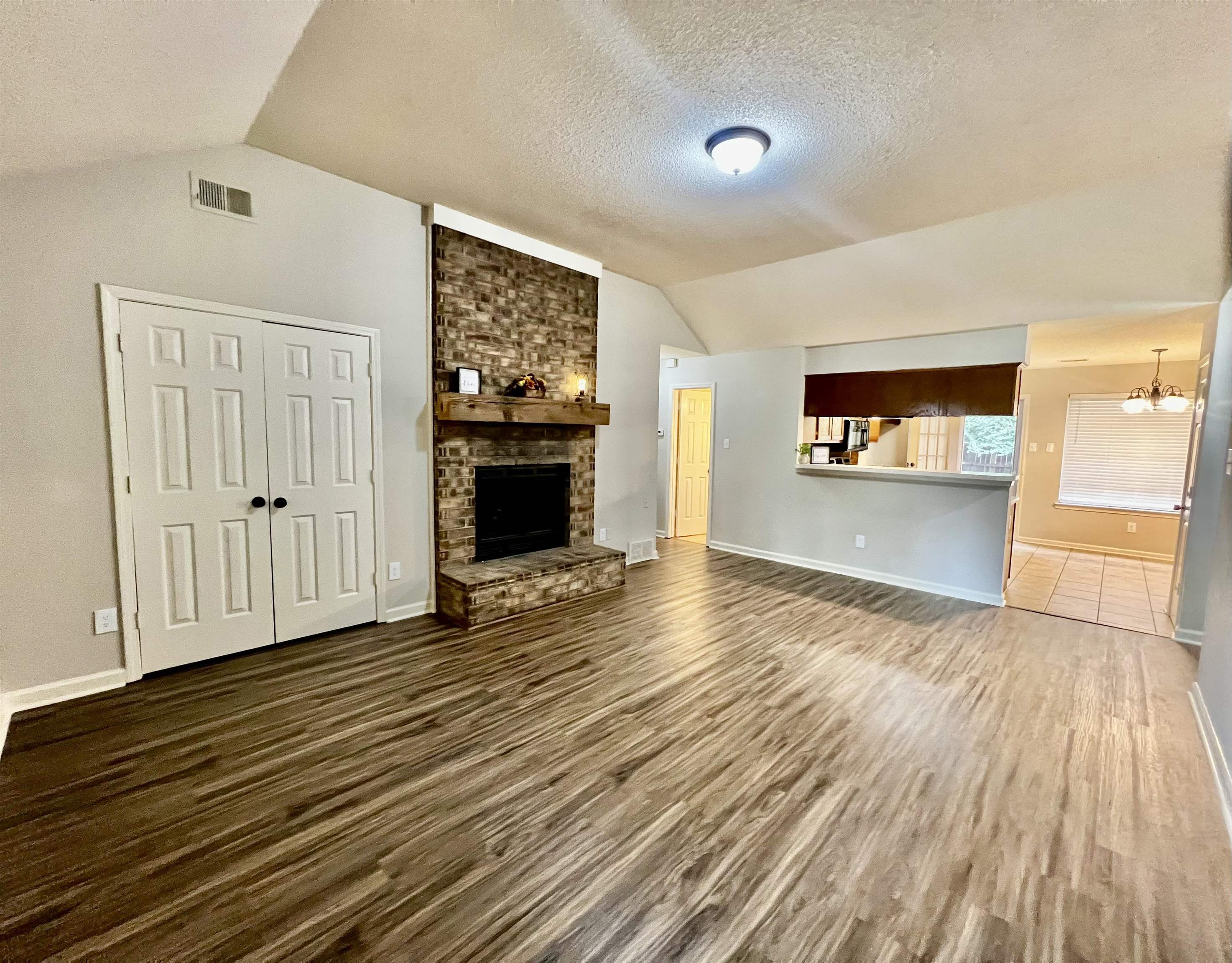 1340 Lagrange Downs Road Cordova, TN 38018 - Photo 2 of 23 Unfurnished living room with dark wood-type flooring, lofted ceiling, a textured ceiling, and a brick fireplace