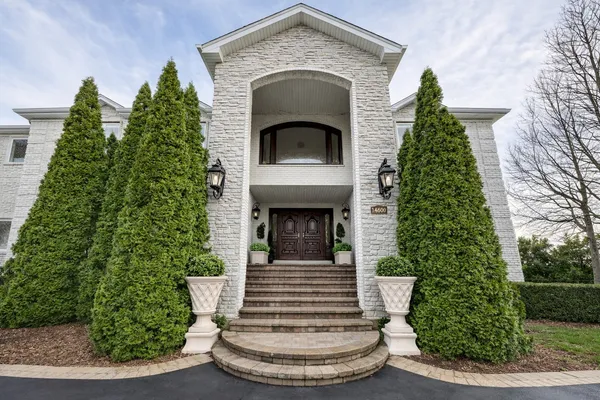 a view of a house with a small yard plants and large tree
