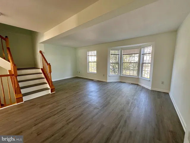 a view of an empty room with wooden floor and fan