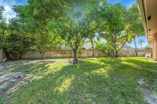 a front view of a house with a garden and palm trees