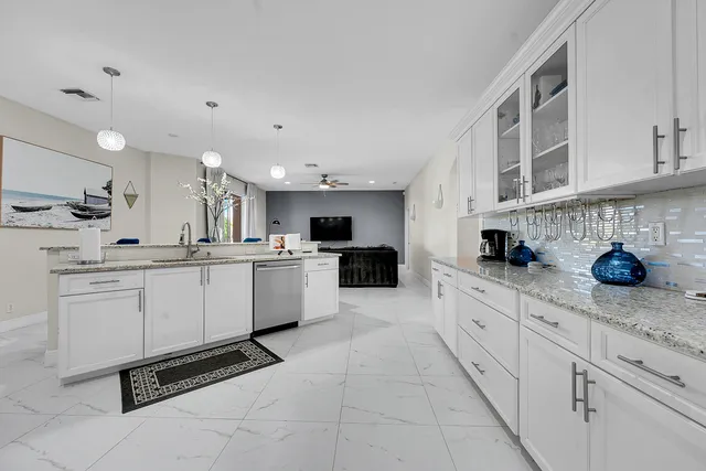 a kitchen with granite countertop a sink stainless steel appliances and white cabinets