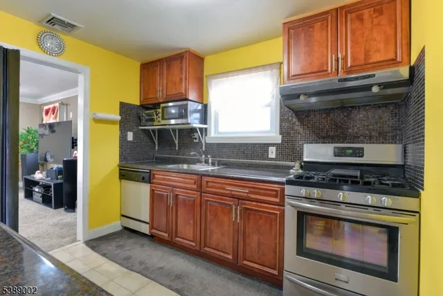a kitchen with stainless steel appliances granite countertop a stove a sink and a microwave