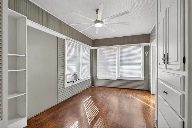a view of an empty room with a window and wooden floor