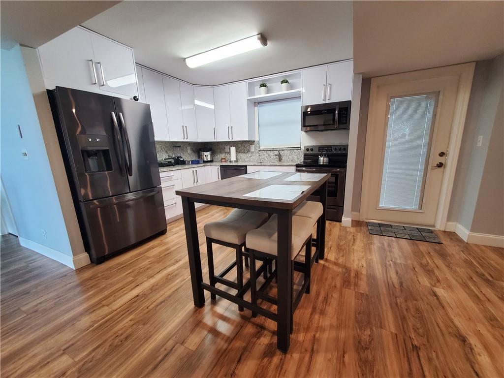 1401 North Riverside Drive, Unit 1503 Pompano Beach, FL 33062 - Photo 15 of 34 a kitchen with stainless steel appliances a refrigerator a stove a sink dishwasher and a dining table with wooden floor