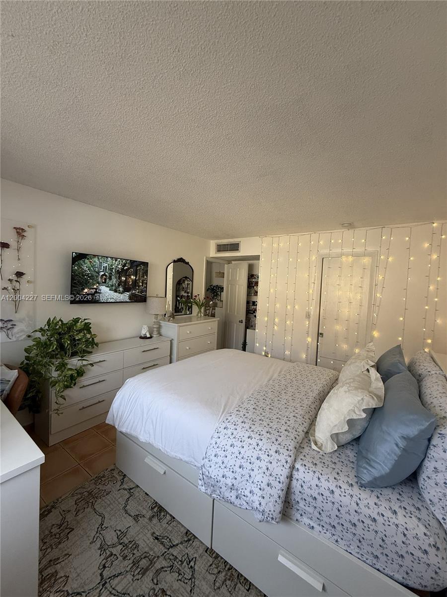 15650 Southwest 80th Street, Unit F208 Miami, FL 33193 - Photo 15 of 19 a bedroom with a large bed and potted plant