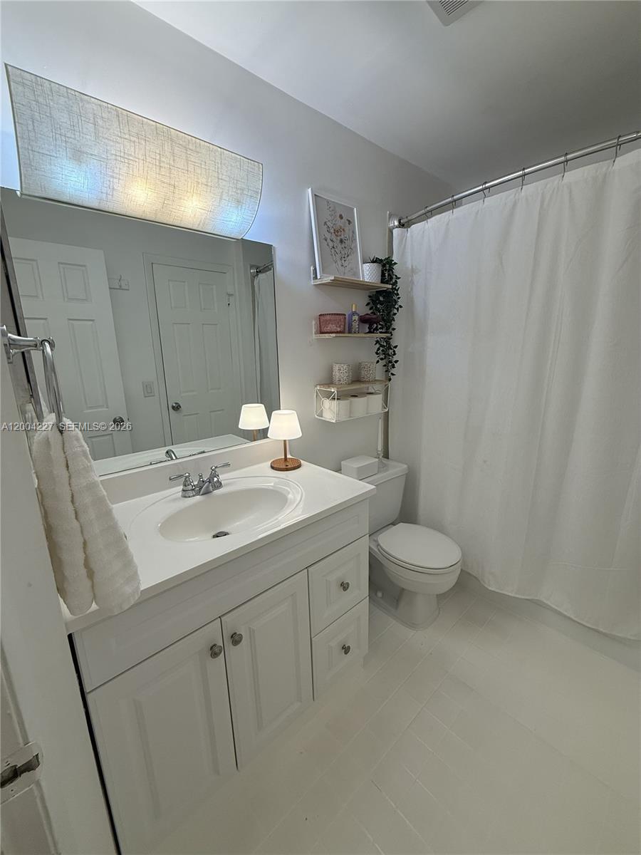15650 Southwest 80th Street, Unit F208 Miami, FL 33193 - Photo 16 of 19 a bathroom with a sink toilet a mirror a vanity and shower