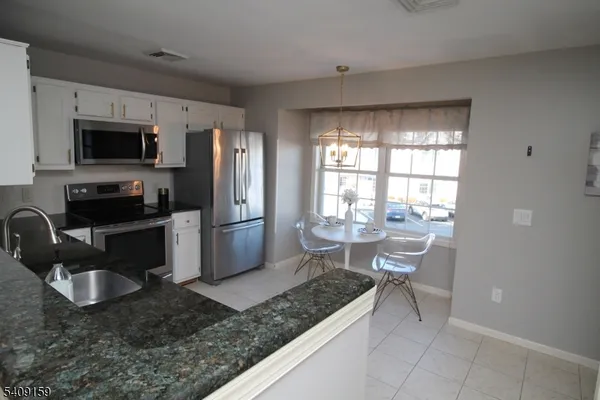 a kitchen with stainless steel appliances granite countertop a sink dishwasher refrigerator stove and microwave