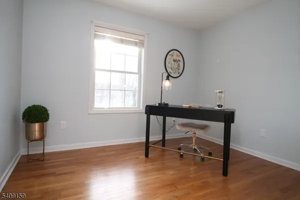 a view of a workspace room with wooden floor and furniture