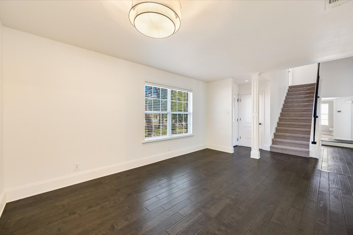 8806 El Rey Boulevard Austin, TX 78737 - Photo 12 of 35 Living room featuring dark wood finished floors, stairs, baseboards and window facing front with natural light