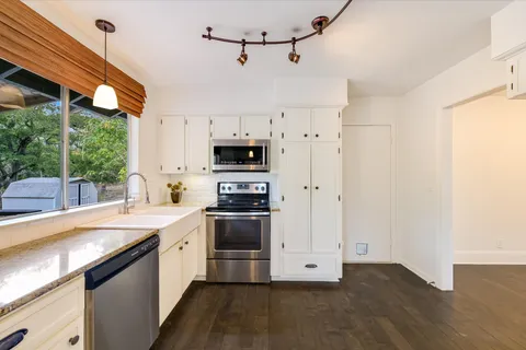 a kitchen with stainless steel appliances a sink a stove a refrigerator cabinets and a window