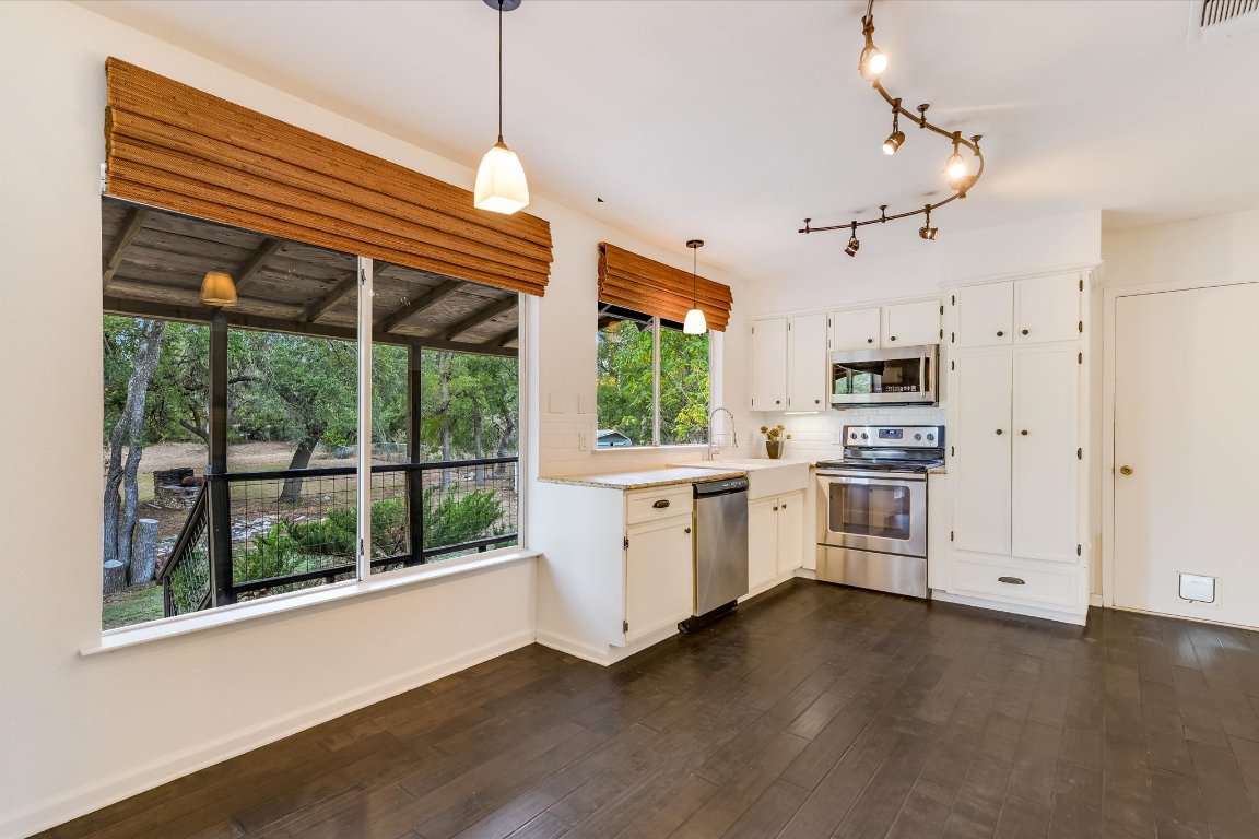 8806 El Rey Boulevard Austin, TX 78737 - Photo 7 of 35 Kitchen featuring appliances with stainless steel finishes, pendant lighting, decorative backsplash, white cabinetry, and dark wood finished flooring