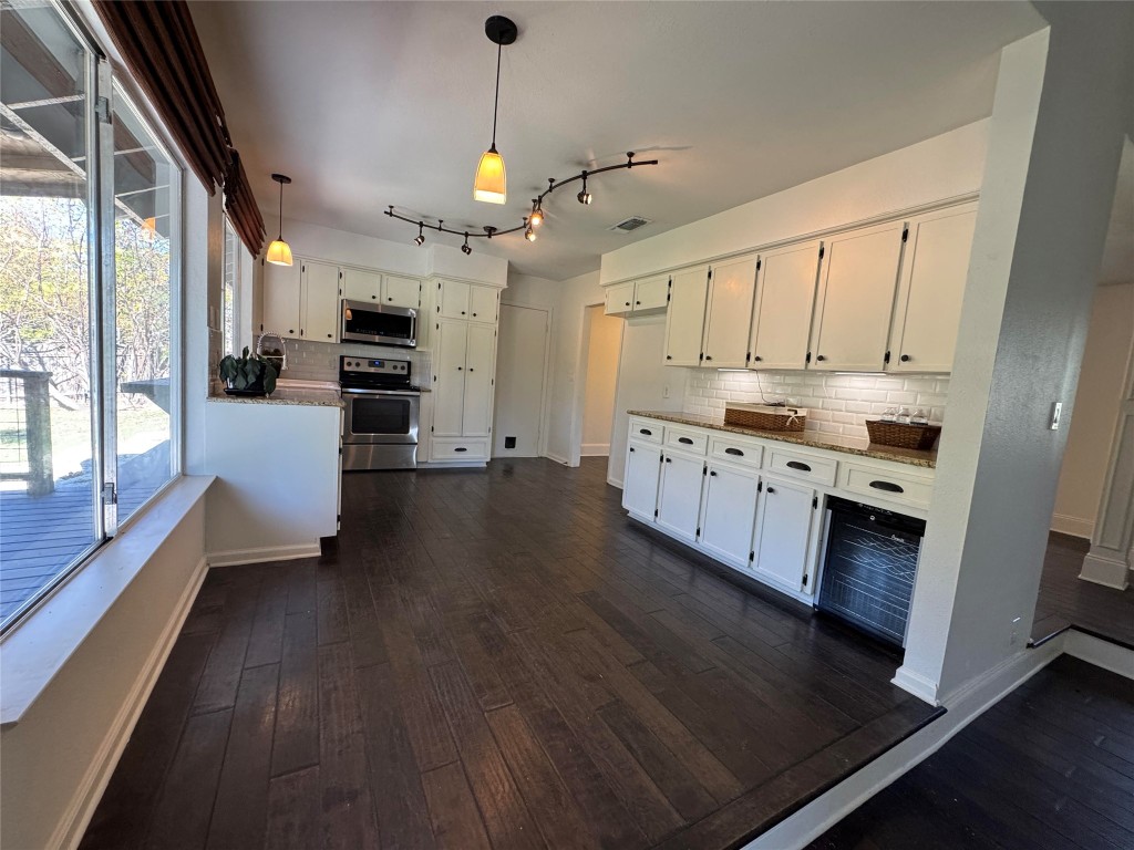 8806 El Rey Boulevard Austin, TX 78737 - Photo 8 of 35 Kitchen featuring tasteful backsplash, pendant lighting, appliances with stainless steel finishes, and white cabinets