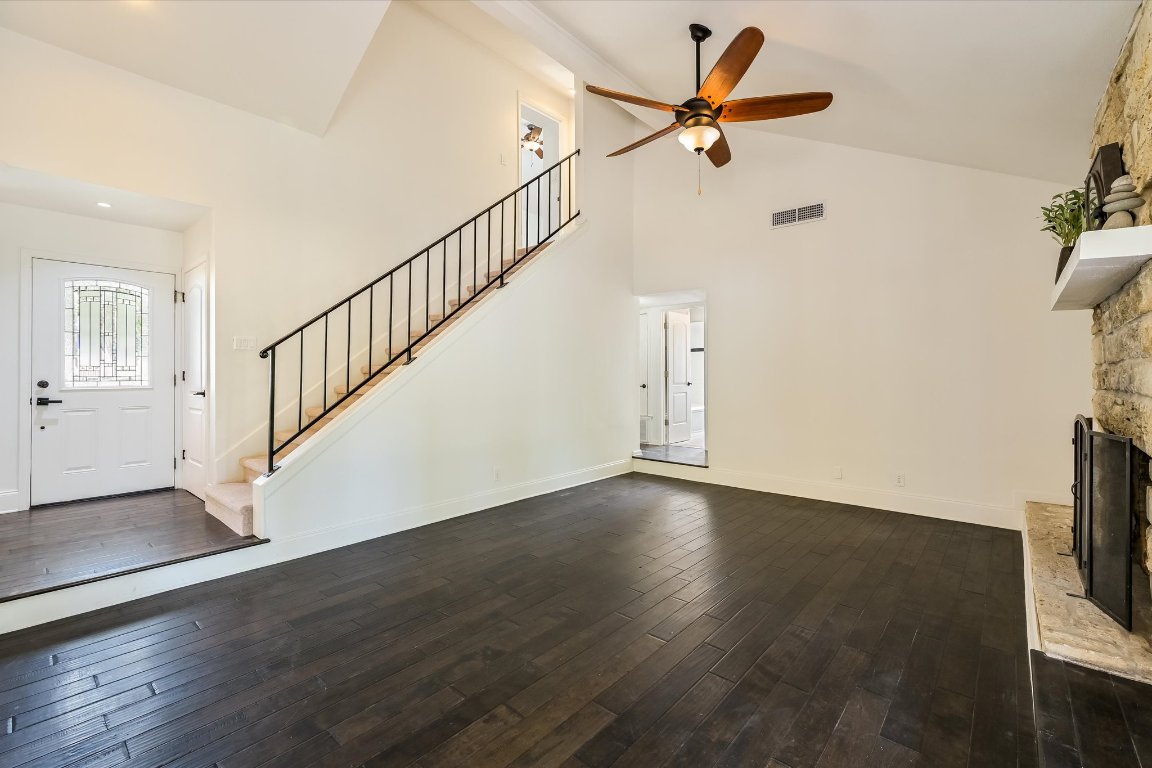 8806 El Rey Boulevard Austin, TX 78737 - Photo 9 of 35 Living room with dark wood finished floors, high vaulted ceiling, a fireplace, stairway, and ceiling fan