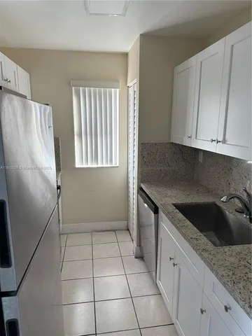 a kitchen with granite countertop a refrigerator a sink a stove a microwave and cabinets