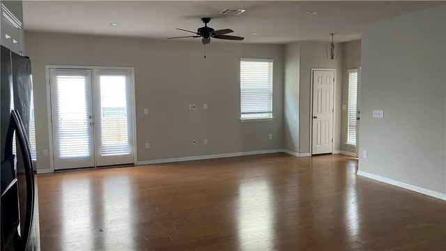 an empty room with wooden floor fan and windows