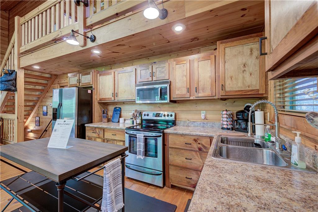 774 Kelly Ridge Drive Blue Ridge, GA 30513 - Photo 25 of 99 a kitchen with stainless steel appliances granite countertop a stove top oven a sink dishwasher and cabinets with wooden floor