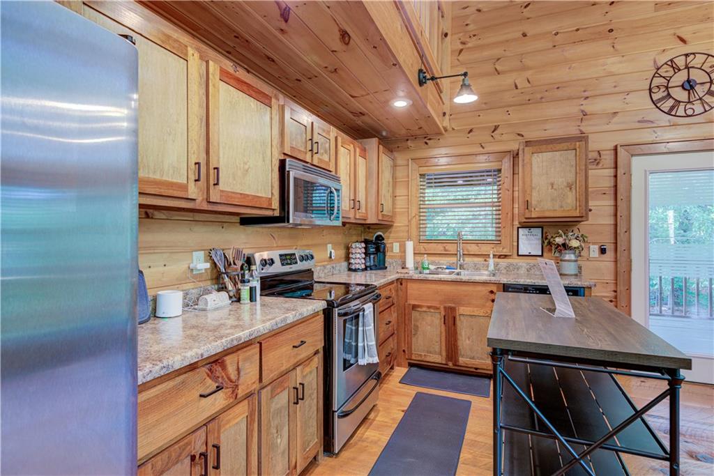 774 Kelly Ridge Drive Blue Ridge, GA 30513 - Photo 26 of 99 a kitchen with stainless steel appliances granite countertop a stove a sink dishwasher a microwave oven and a dining table with wooden cabinet