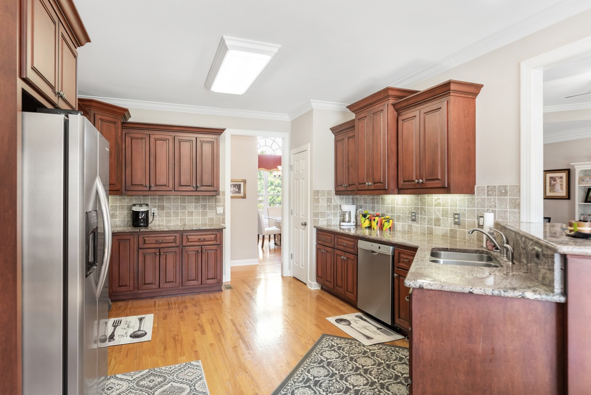 105 Robin Point Gallatin, TN 37066 - Photo 21 of 59 a kitchen with granite countertop wooden cabinets a sink a stove a refrigerator and island with wooden floor