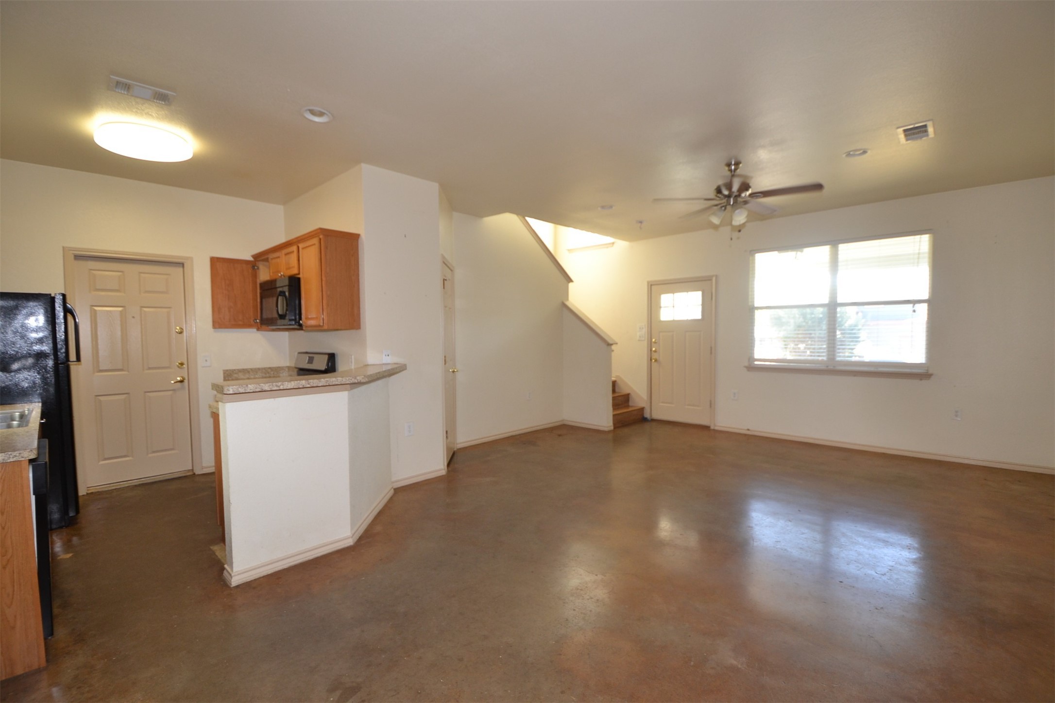 6912 Meador Avenue, Unit A Austin, TX 78752 - Photo 22 of 22 Kitchen featuring open floor plan, wood finish cabinetry, concrete flooring, light countertops, and black appliances