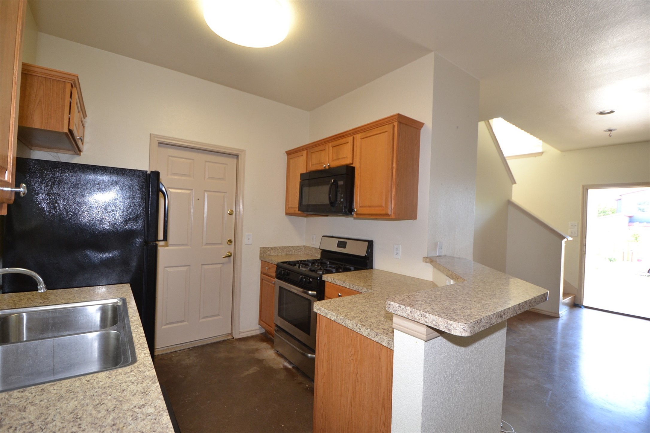 6912 Meador Avenue, Unit A Austin, TX 78752 - Photo 5 of 22 Kitchen with black appliances, concrete floors, a peninsula, and light countertops