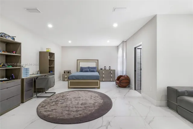 a spacious bedroom with a large bed a flat tv screen and a chandelier