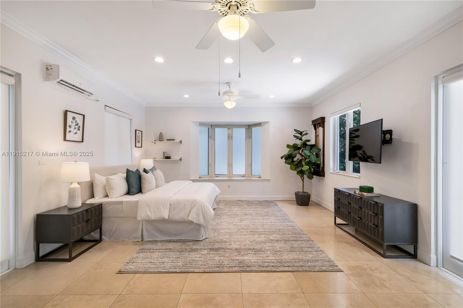 8941 Southwest 65th Court, Unit 8941 Pinecrest, FL 33156 - Photo 46 of 85 a spacious bedroom with a large bed a flat tv screen and a chandelier