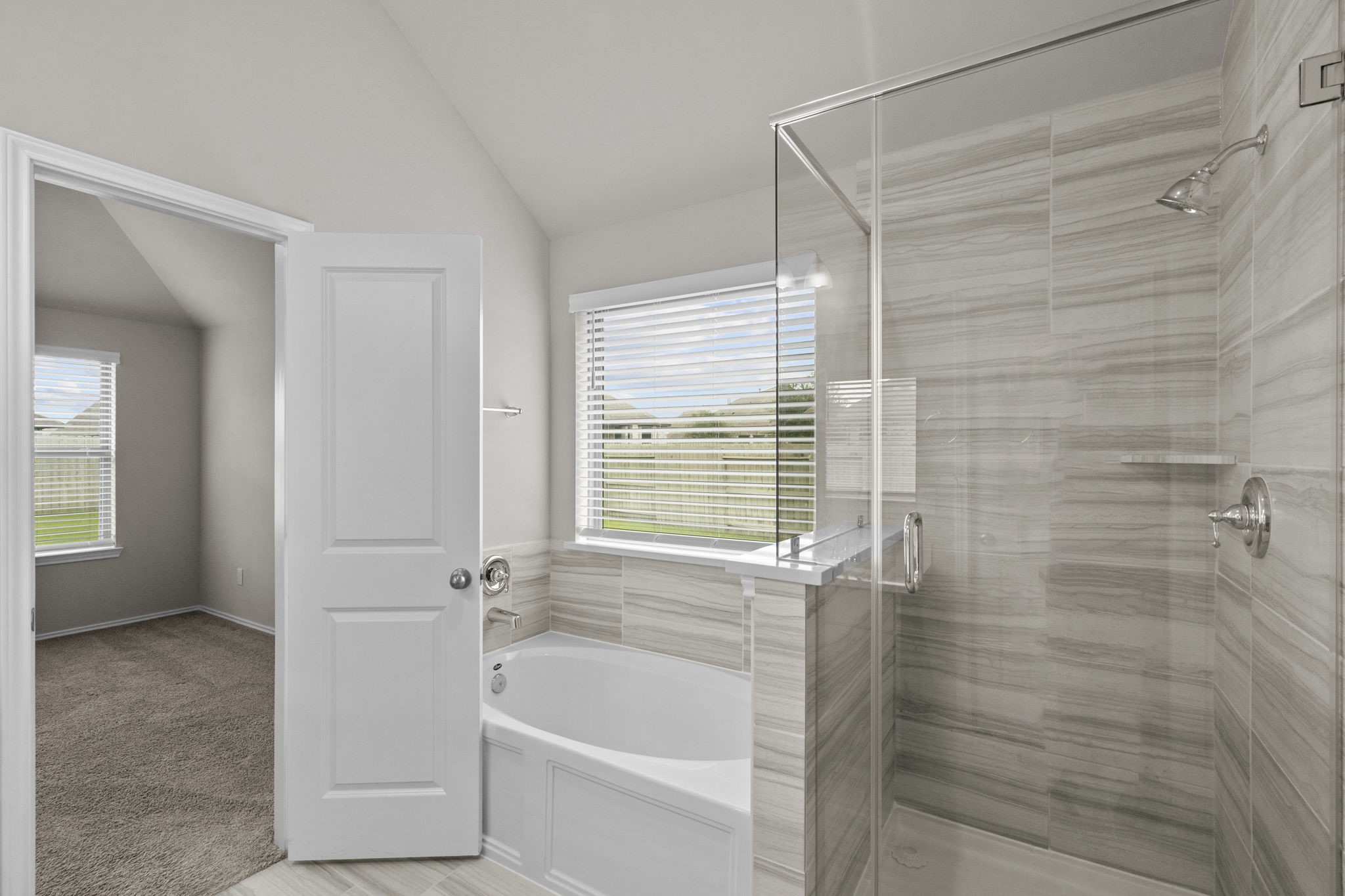 2011 Oak Leaf Court Manvel, TX 77578 - Photo 20 of 28 This bathroom features a modern design with a glass-enclosed shower, a separate bathtub, and a window providing natural light. The room connects to a carpeted area, adding convenience and comfort.