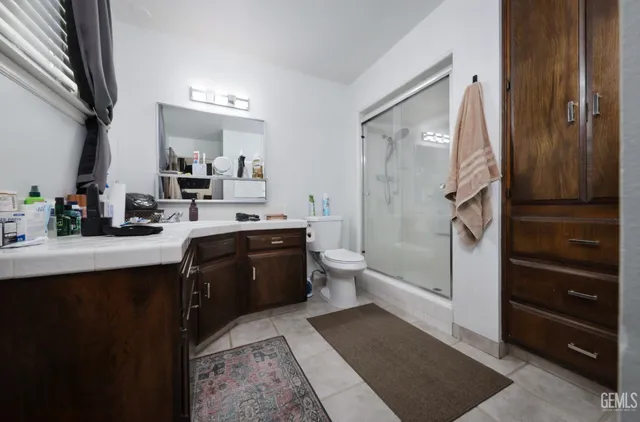 a large bathroom with a double vanity sink a toilet a mirror and shower