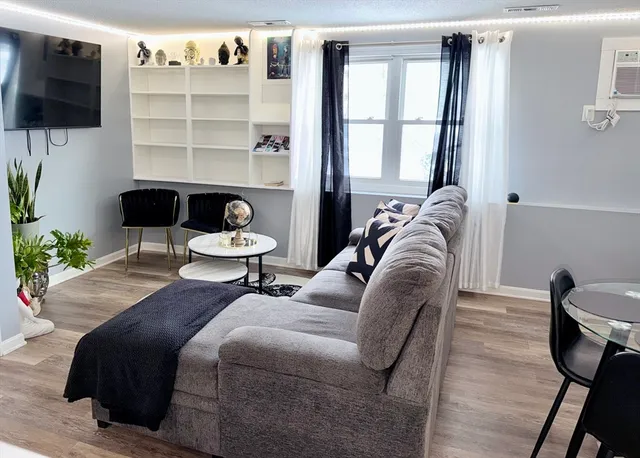 a living room with furniture a flat screen tv and a floor to ceiling window